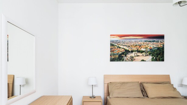 A bedroom with a bed, bedside tables, a nightstand, a lamp, and a cityscape view. - Flatty Apartments - Camillo Vacani (Milan)