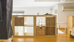 A room with a wooden partition, a small table with a cup and book, and an air conditioning unit on the wall.