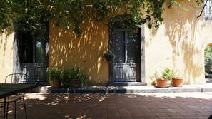 A building with a yellow facade, black doors, and potted plants. - Malvarosa (Giarre)