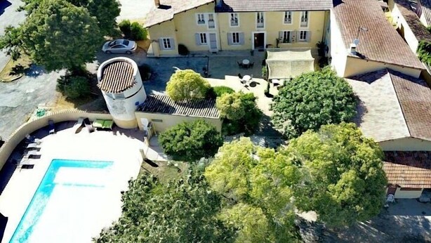 Vista aérea de una propiedad con piscina, un edificio grande con múltiples ventanas y vegetación circundante.