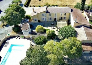 An aerial view of a property with a swimming pool, a large building with multiple windows, and surrounding greenery. - Hôtel Le Mas Des Quintrands (Manosque)