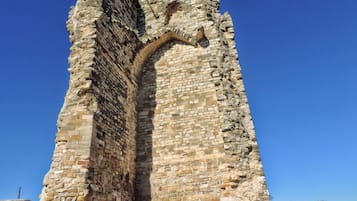 Une tour de pierre dotée d’un étroit passage, entourée d’herbe et de rochers.