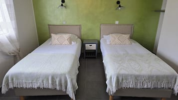 Habitación doble con dos camas, una mesita de noche pequeña y una pared verde.