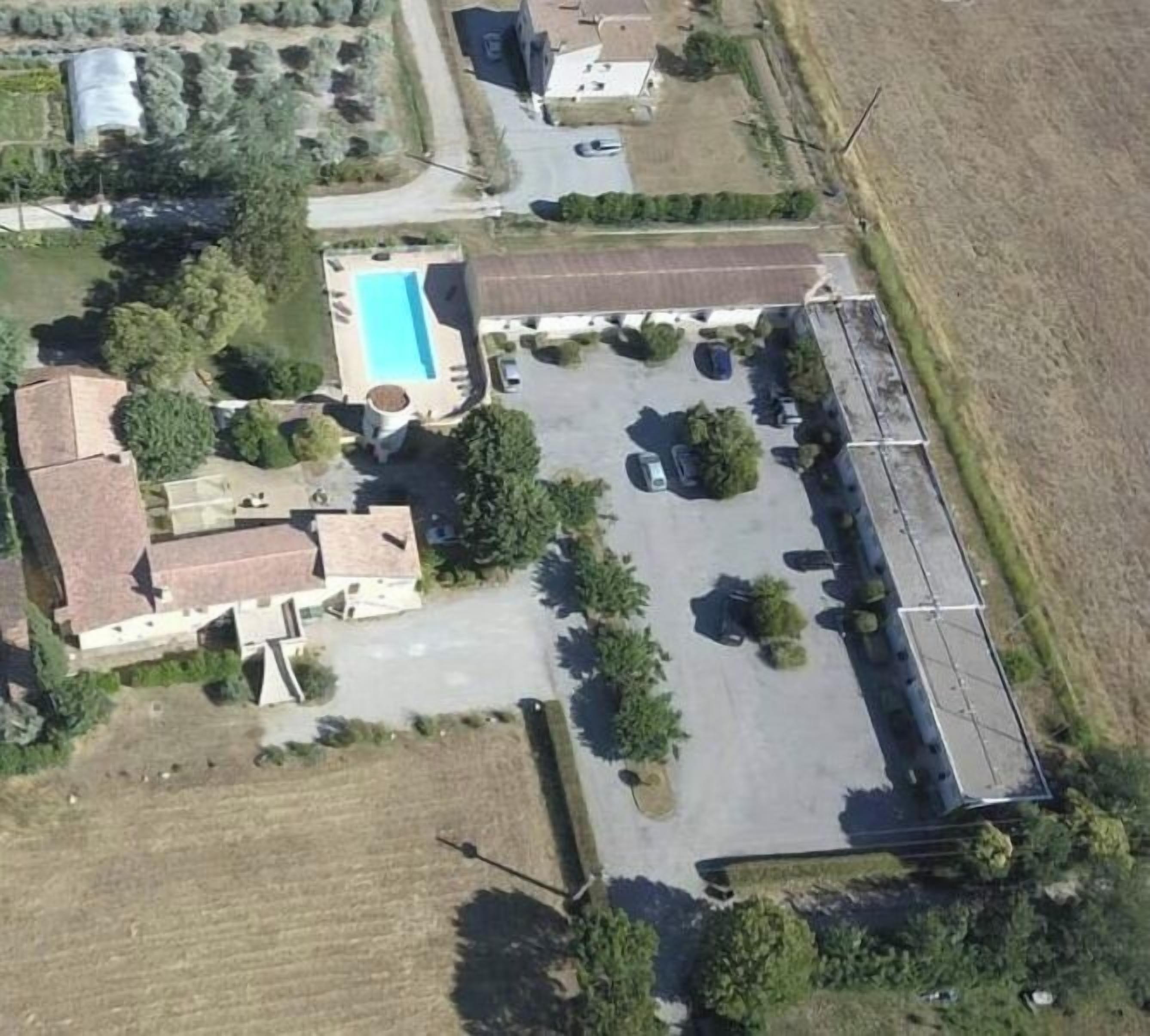 Oversigtsbillede af et boligområde med en swimmingpool, en parkeringsplads og flere huse.