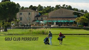 Un club de golf con un césped cuidado, una casa club y zonas de estar al aire libre.
