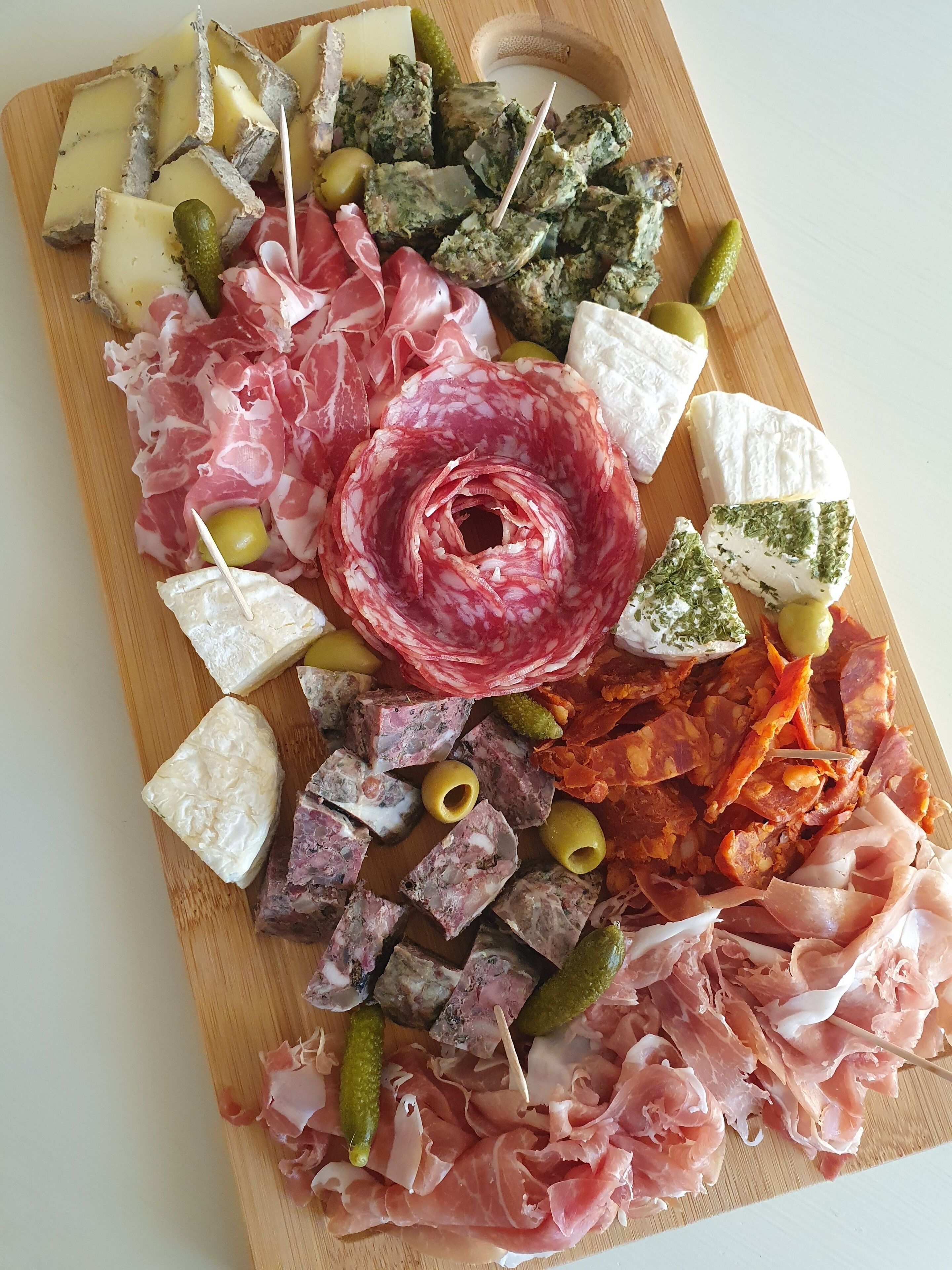 A charcuterie board with various meats, cheeses, and olives.
