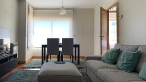 Una sala moderna con un sofá, un reposapiés y una mesa de comedor con sillas.