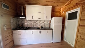 A compact kitchen with white cabinets, a built-in stove, and a refrigerator.