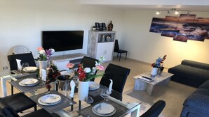 Een moderne woonkamer met een eethoek, een flatscreen televisie en een open haard.