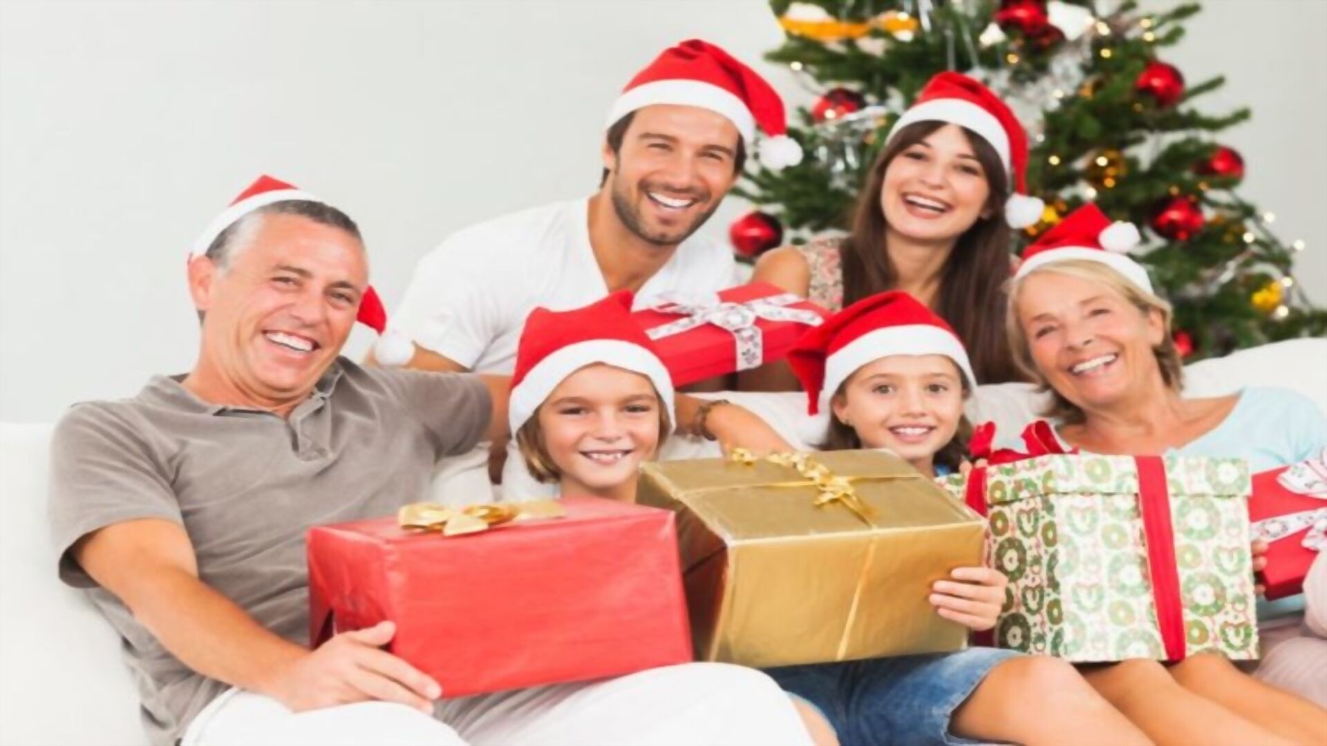 Een gezin zit op een bank, met een kerstboom op de achtergrond.