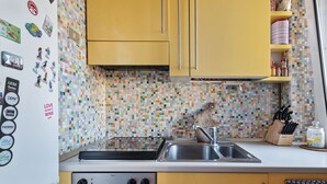 Cozinha com armários amarelos, painel de azulejos, fogão e pia.