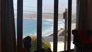 Ein Zimmer mit großem Fenster und Meerblick, einer Couch und einem Sessel.