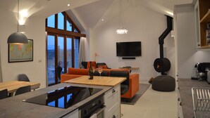 Ein modernes Wohnzimmer mit großem Fernseher, Kamin und einer gemütlichen Sitzecke.