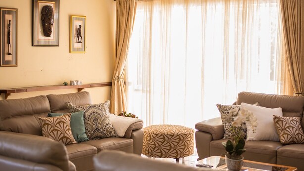 A living room with two sofas, patterned cushions, a coffee table with a plant, and framed artwork on the wall. - Eden Villas (Harare)