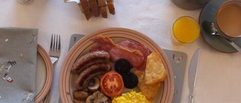Une assiette de petit-déjeuner comprenant des saucisses, du bacon, des champignons, des œufs brouillés et des toasts.