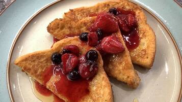 Un plato con tres rebanadas de tostada triangular adornadas con bayas y jarabe.