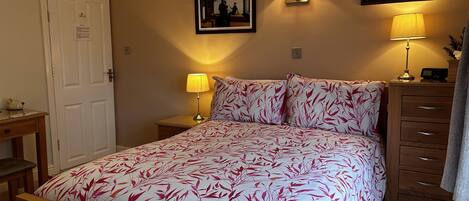 A bedroom with a bed, bedside tables, a dresser, and wall-mounted lamps.