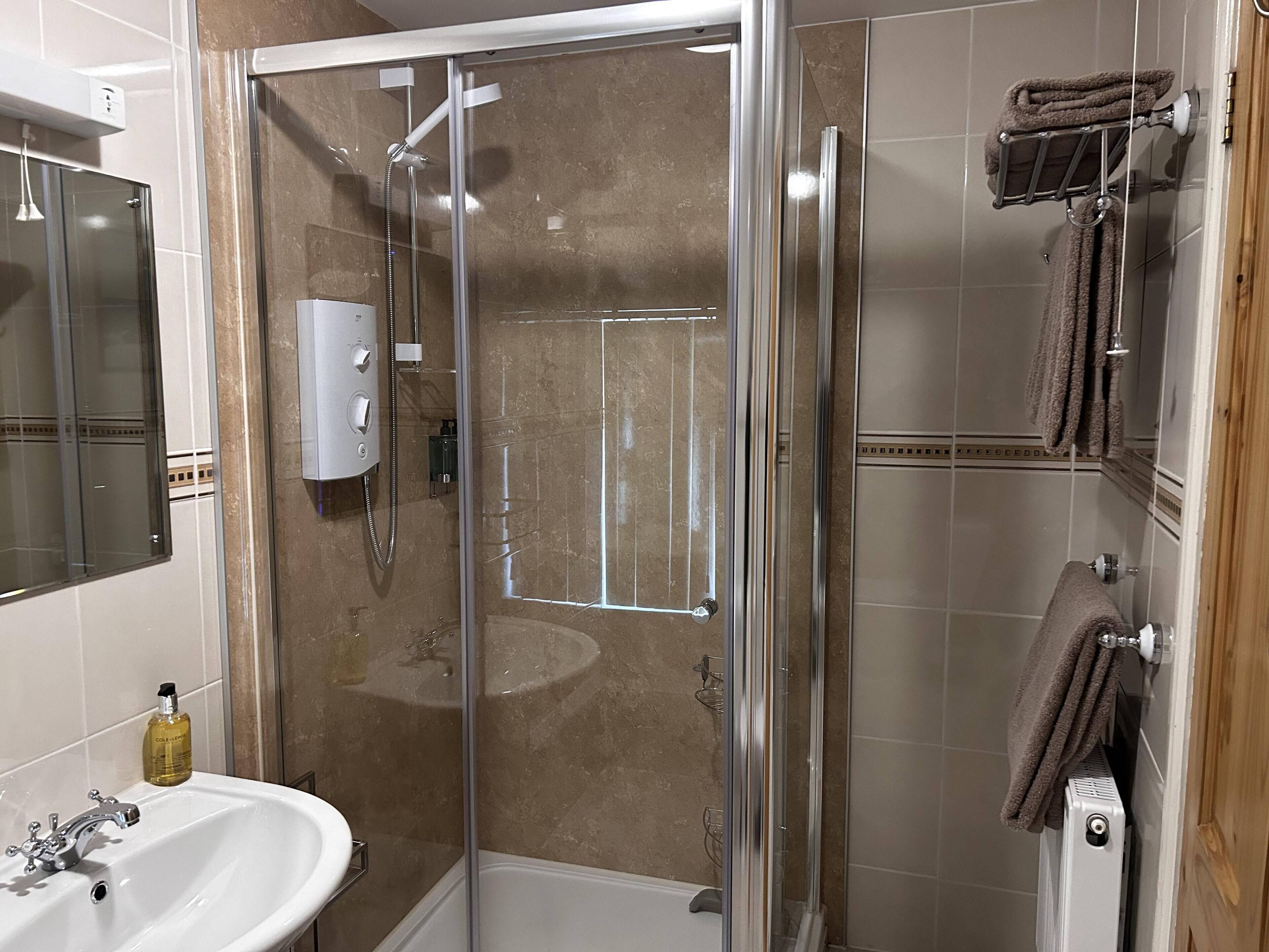 Ein modernes Badezimmer mit einer Glasdusche, einem Waschbecken und einem Handtuchhalter.