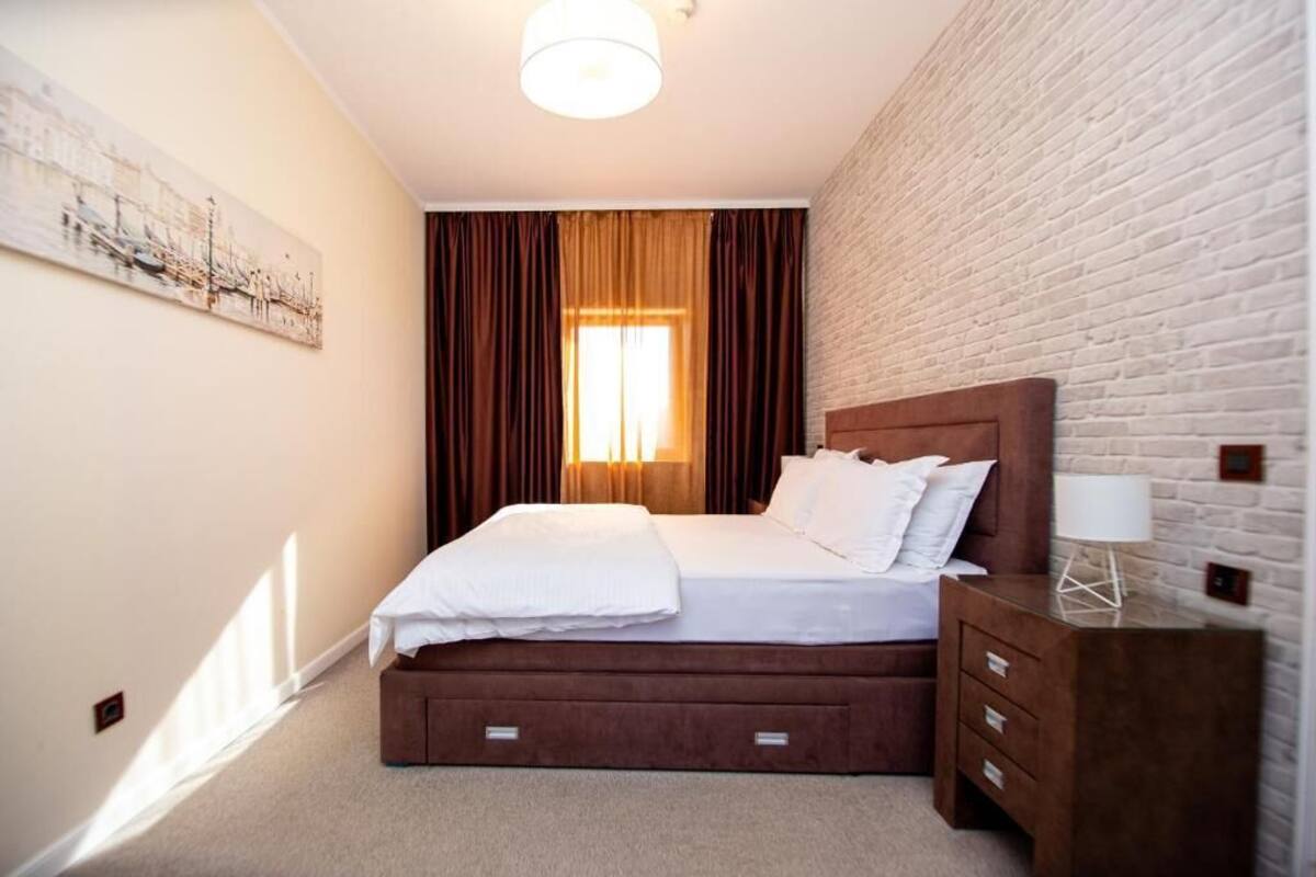 A bedroom with a bed, a nightstand, a lamp, and a painting on the wall.