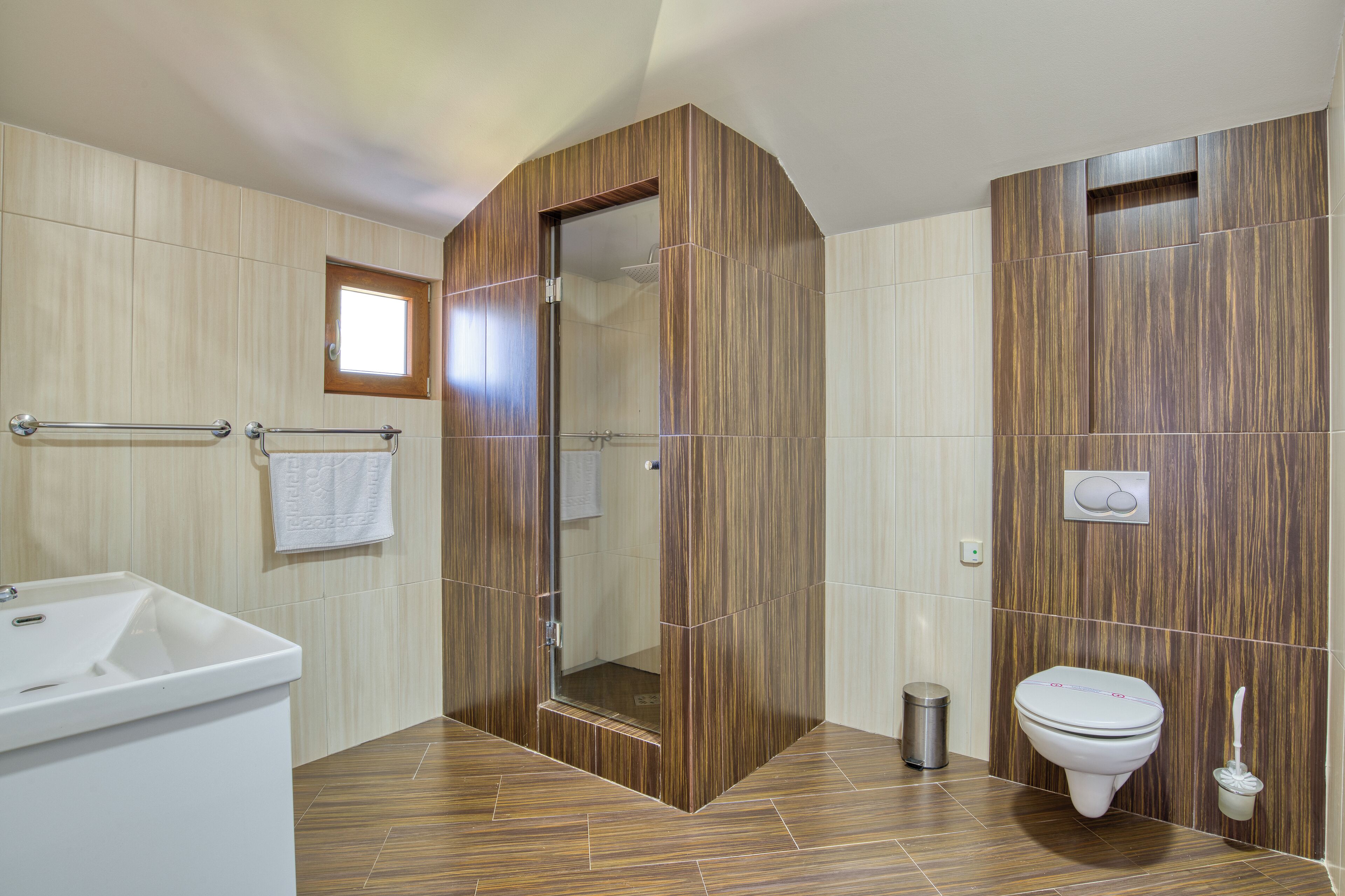 A bathroom with a wooden vanity, a toilet, and a shower area.