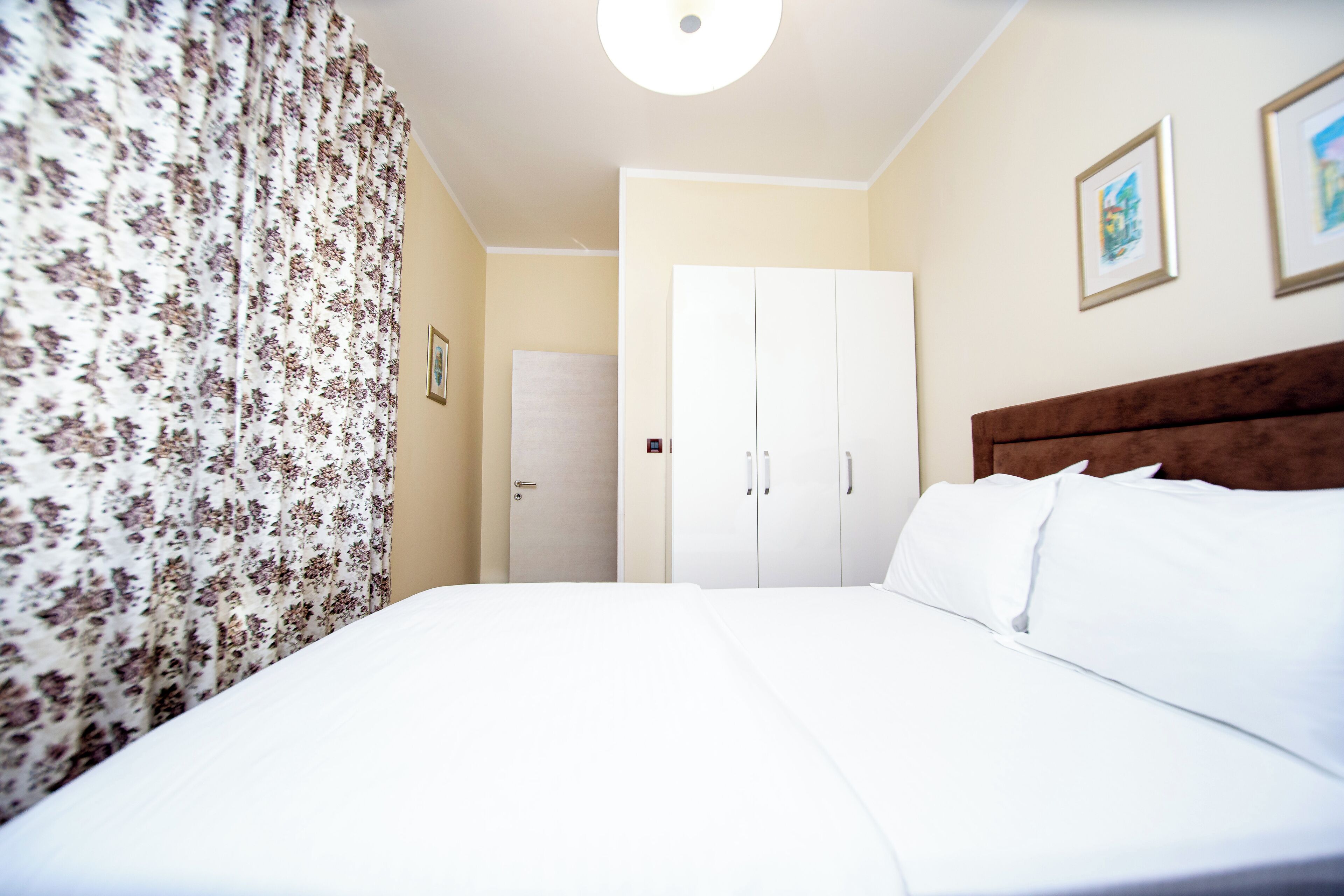 Ein Hotelzimmer mit einem großen Bett, einem Holzkopfstück, einem Kleiderschrank und einer Tür.
