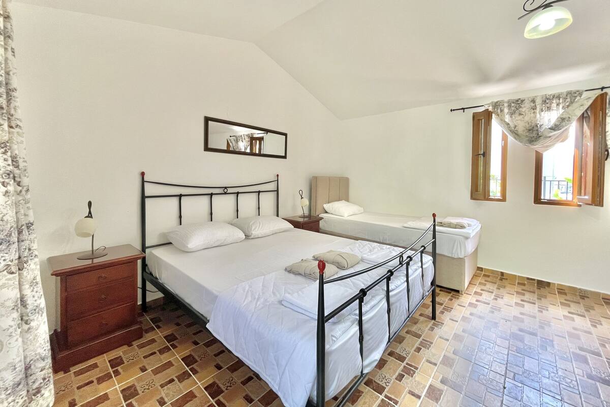 A bedroom with a bed, a nightstand, a dresser, a mirror, and a window with curtains.