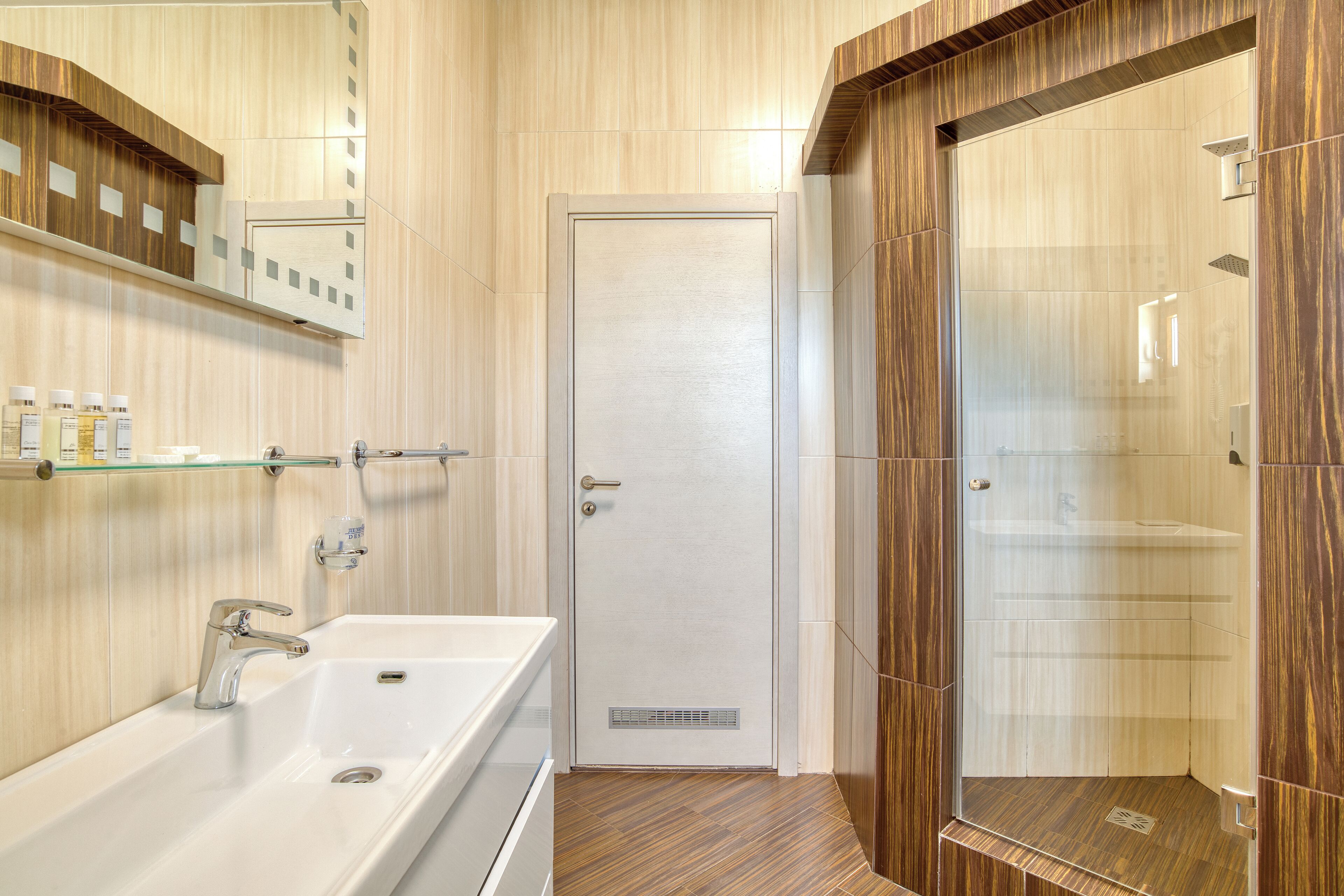 Ein modernes Badezimmer mit Waschbecken in Weiß, einer Duschkabine aus Glas und Holzvertäfelung.