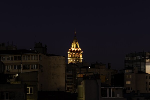 A nighttime cityscape with a prominent illuminated tower in the center.
