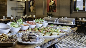 Een buffet met diverse gerechten, waaronder salades, vleeswaren en desserts, in een restaurant met modern interieur en kunstwerken aan de muren.