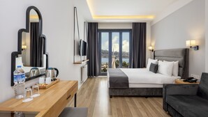 Een hotelkamer met een bed, een bureau, een stoel, een bank, een televisie, een spiegel en uitzicht op de stad.