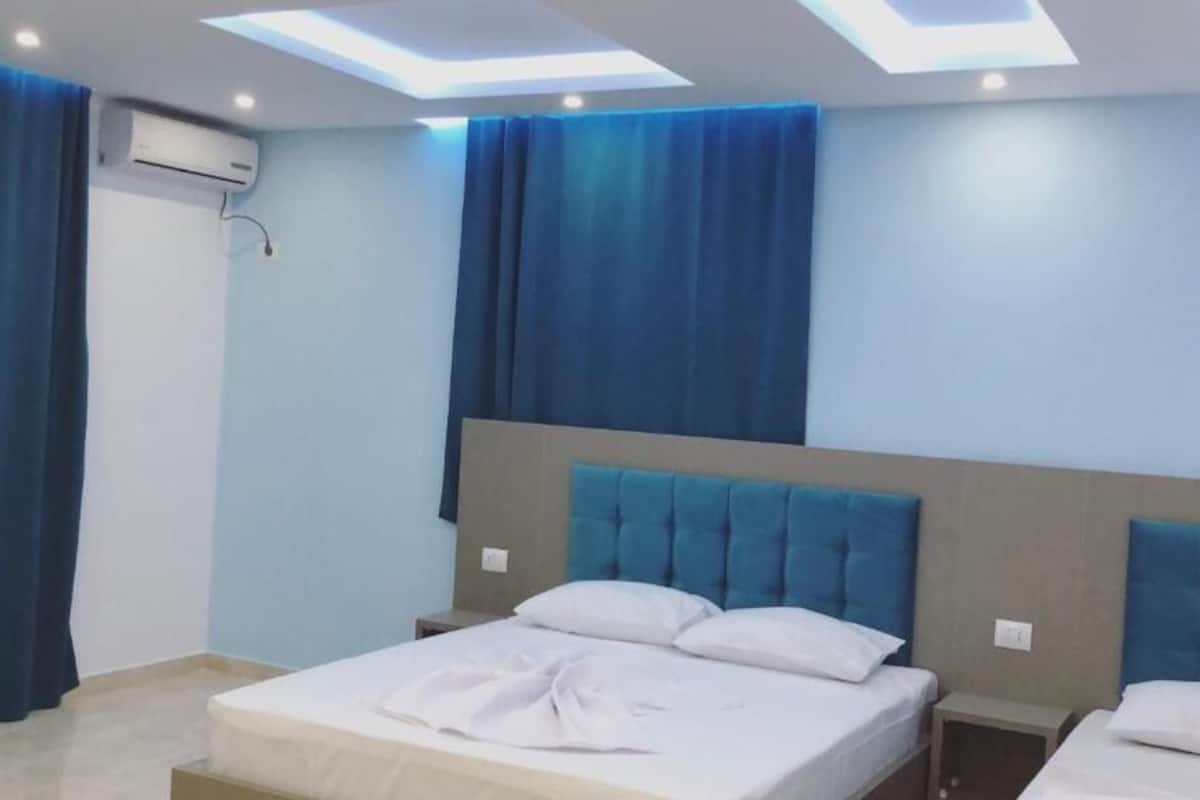 A bedroom with a bed, two bedside tables, and a ceiling light fixture.