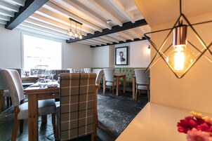 Comedor con mesa de madera, sillas e iluminación colgante moderna.