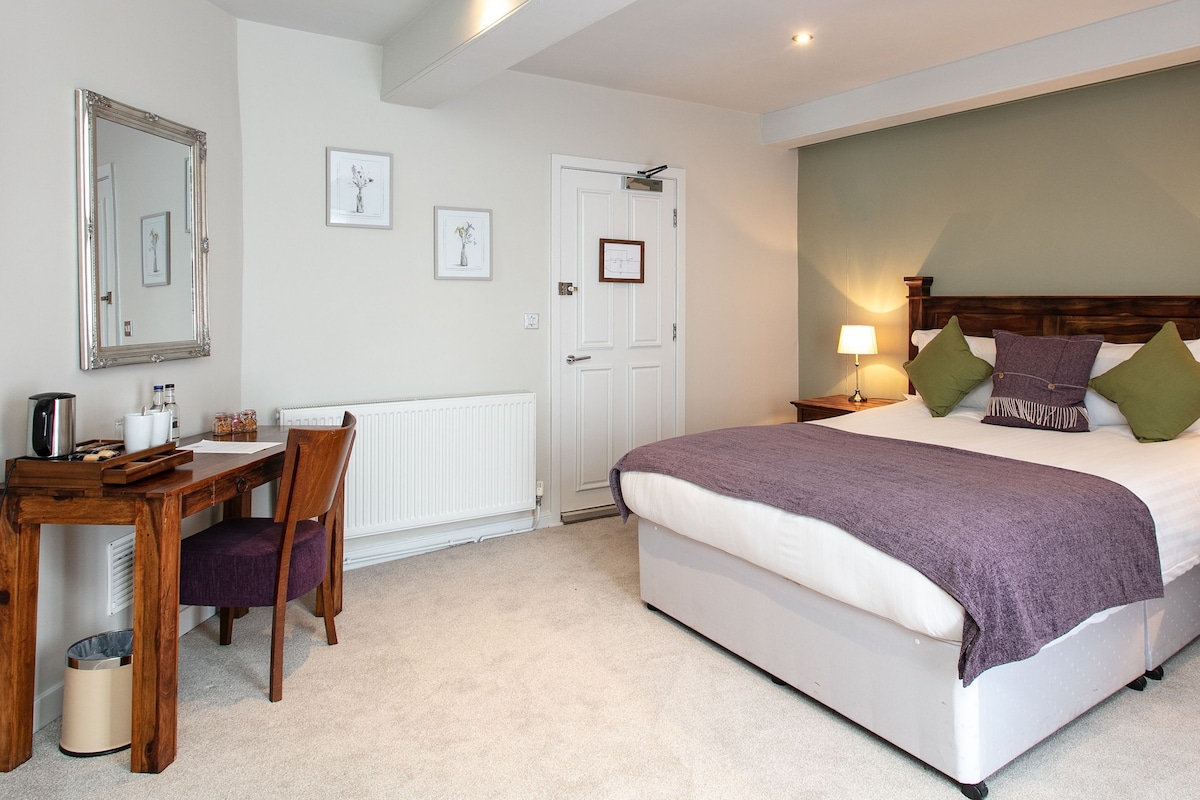 A bedroom with a bed, bedside tables, a desk, and a chair.