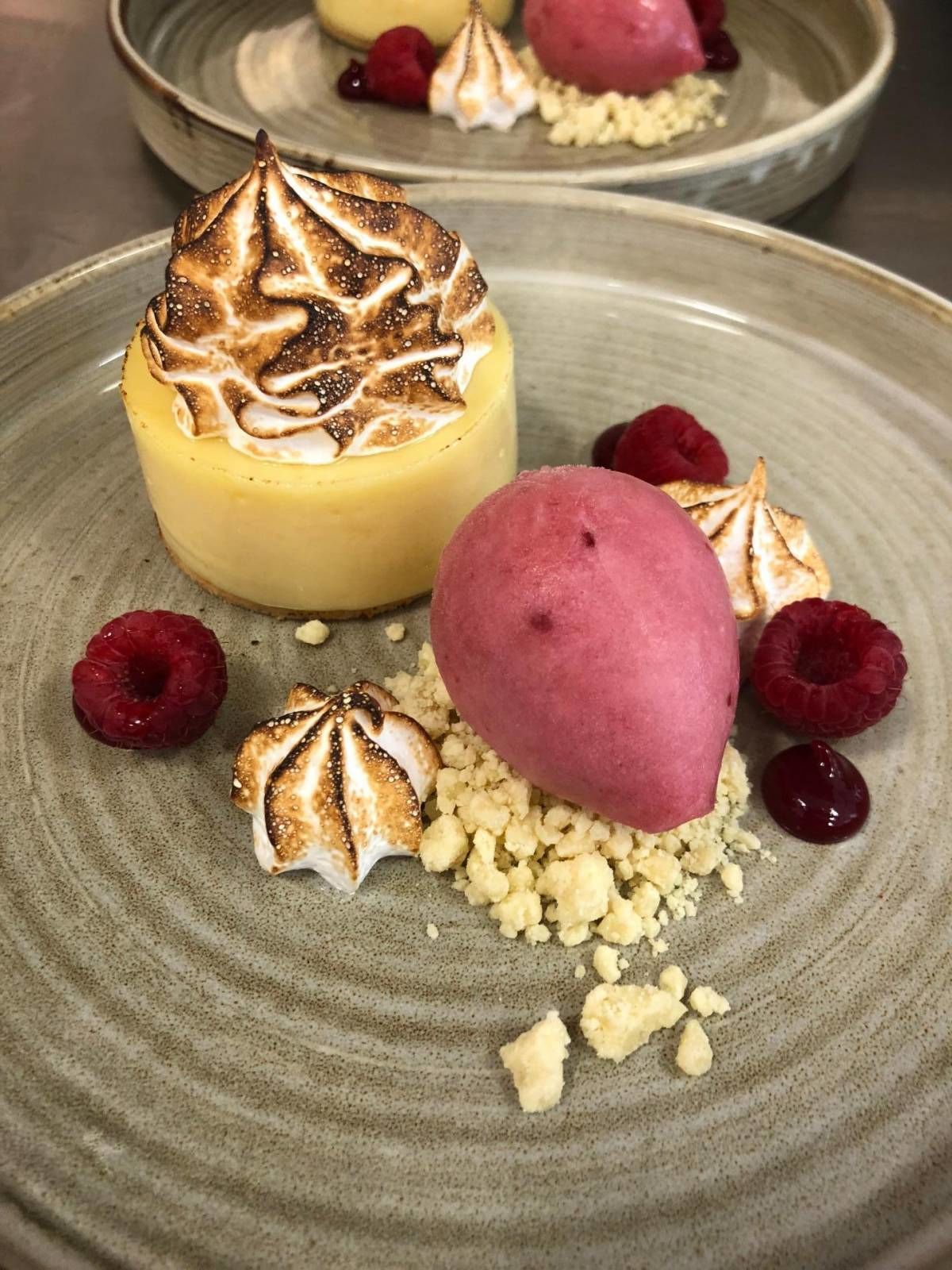 A dessert plate with a yellow cheesecake, a pink ice cream, and meringue-topped marshmallows.