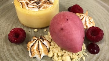 A dessert plate with a yellow cheesecake, a pink ice cream, and meringue-topped marshmallows.