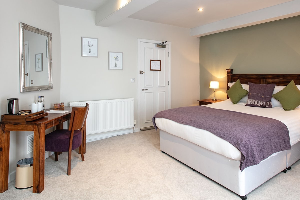 A bedroom with a bed, bedside tables, a desk, and a chair.