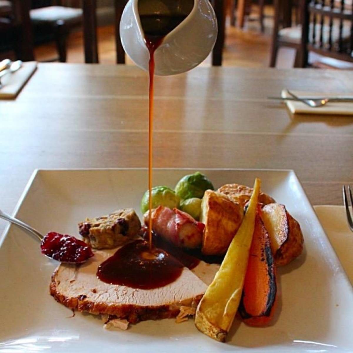 Une assiette remplie de différents aliments, notamment une tranche de viande, des légumes et une sauce versée dessus.