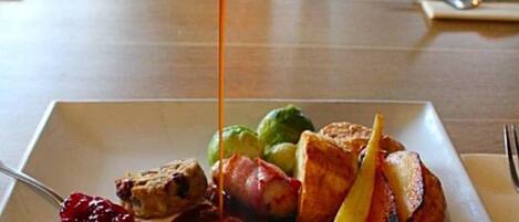Une assiette remplie de différents aliments, notamment une tranche de viande, des légumes et une sauce versée dessus.