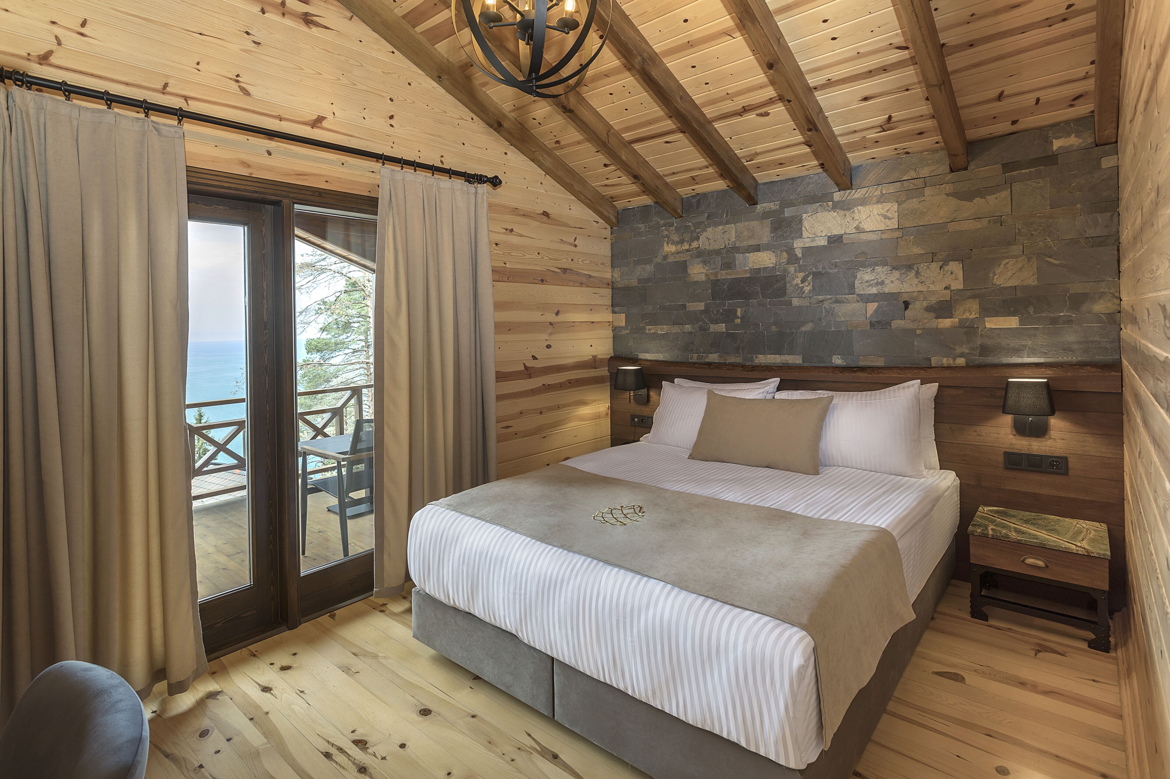 Un dormitorio de cabaña de madera con una cama, una mesita de noche y una pared de piedra.