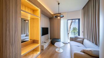 Una sala moderna con una pared de acento de madera, un sofá, un reposapiés redondo y un televisor montado en la pared.