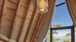 Une chambre avec une grande fenêtre, des poutres en bois et un lit avec des oreillers.
