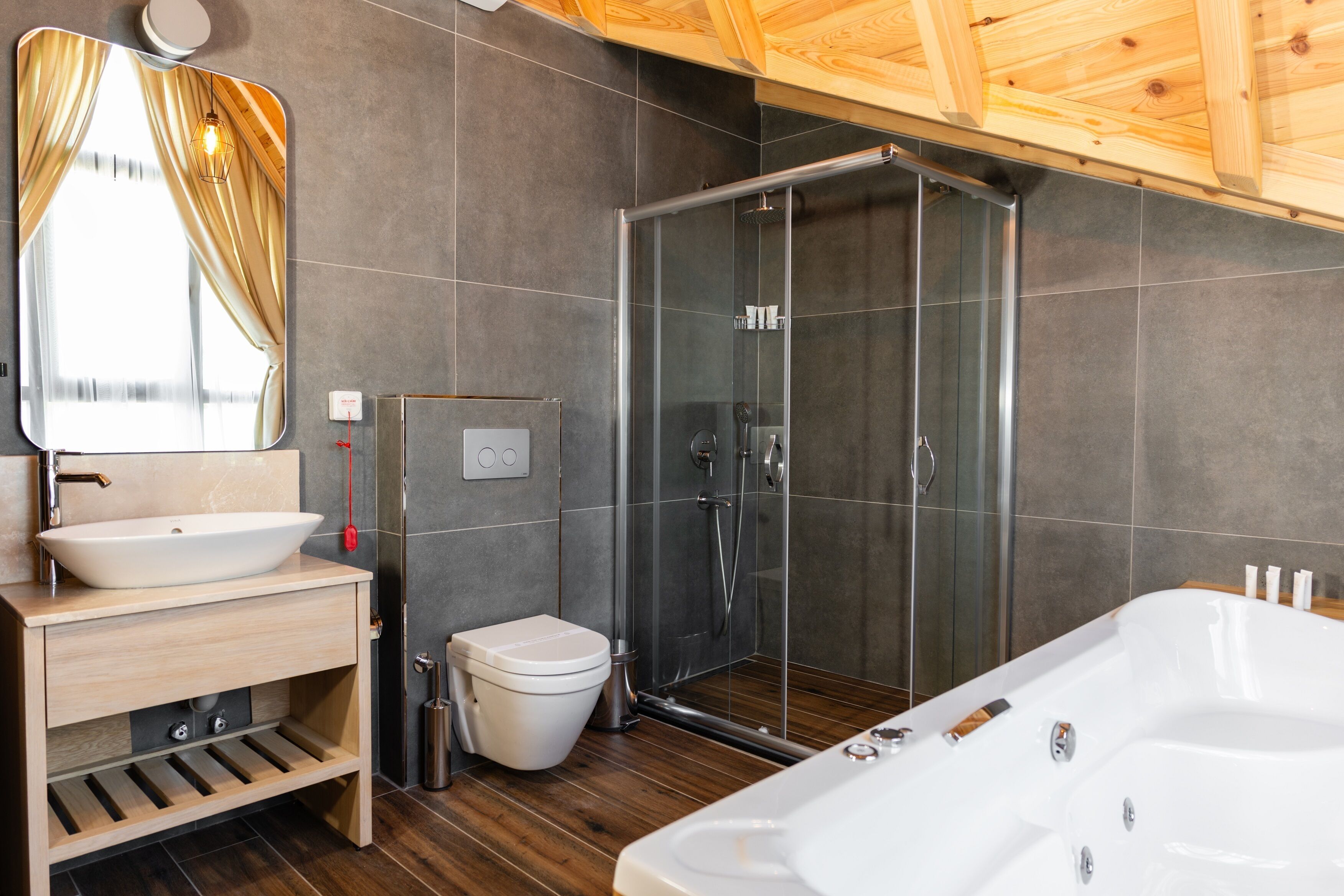 A modern bathroom with a large mirror, a white sink, a toilet, a glass-enclosed shower, and a freestanding bathtub.