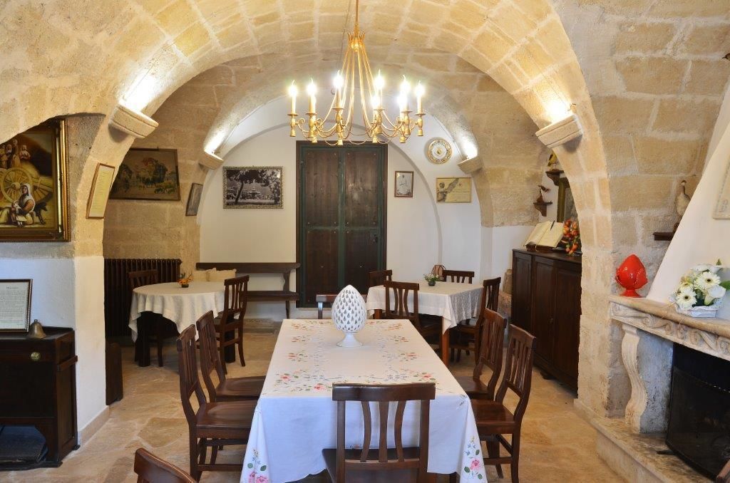 A dining area with stone arches, a chandelier, and a fireplace.