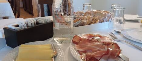 Una mesa con una botella de agua, jamón serrano y una servilleta.