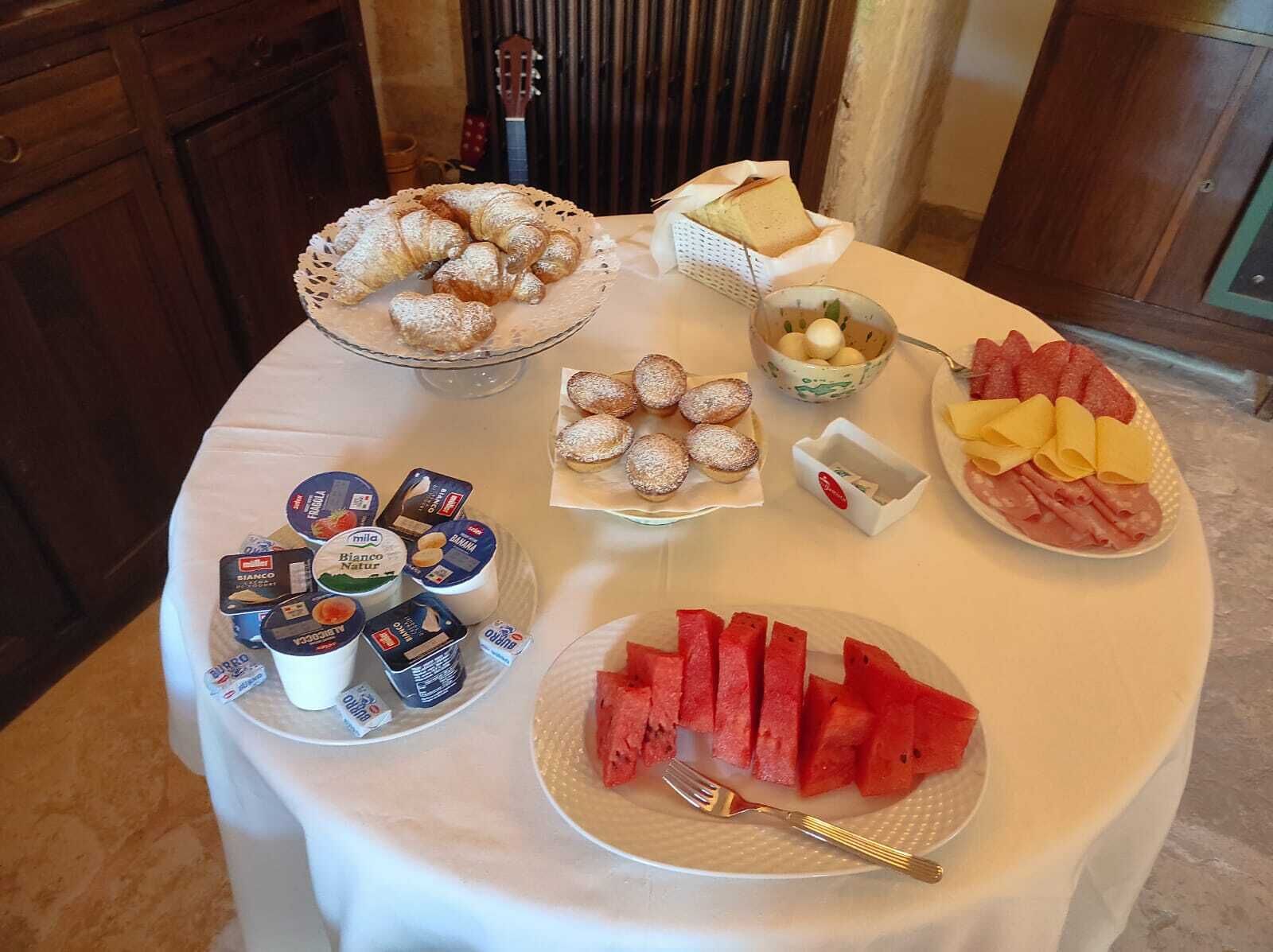 Een ontbijtbuffet met diverse soorten eten, zoals gebak, kaas, ham en schijfjes watermeloen.