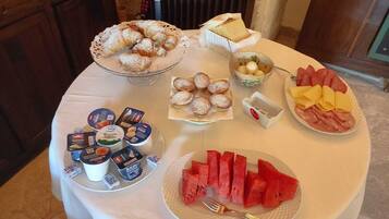 Een ontbijtbuffet met diverse soorten eten, zoals gebak, kaas, ham en schijfjes watermeloen.