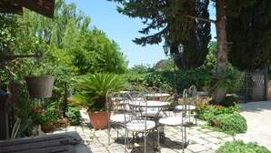 Un patio con giardino, arredi esterni, vasi di piante e un vialetto in pietra.