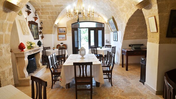 Un'area pranzo con un arco in pietra, un lampadario e un camino.