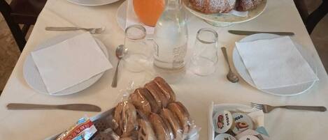 A breakfast table set with plates of pastries, a pitcher of orange juice, and various condiments.