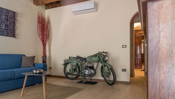 Um quarto com uma motocicleta antiga, um sofá azul e uma mesa pequena.